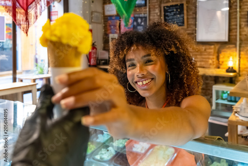 Foto Happy woman receiving yellow ice cream cone in shop