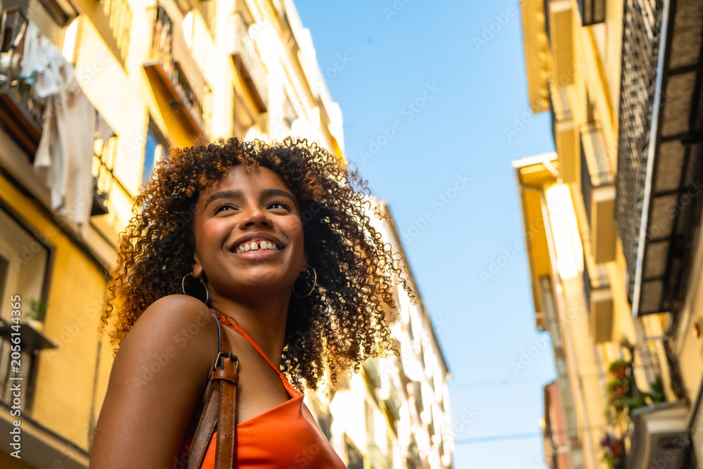 Obraz premium Happy young woman smiling looking up in urban street