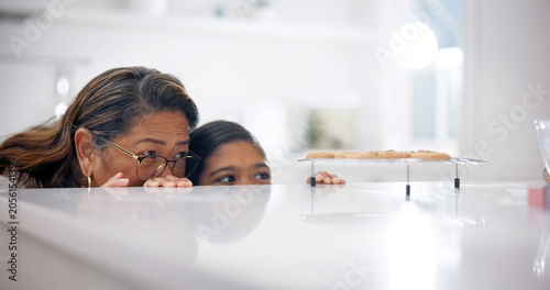 Photos Grandmother, child and sneaky by kitchen counter for cookies, bonding or stealthy for sweet treats