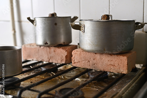 Schilderij op canvas Pots on a stove elevated by bricks, using them to heat the kitchen in the absence of central heating, Ukrainian home context, makeshift method for warmth in cold weather