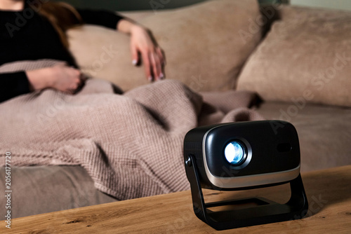 Projector Casts Light While Woman Relaxes on Couch in Living Room