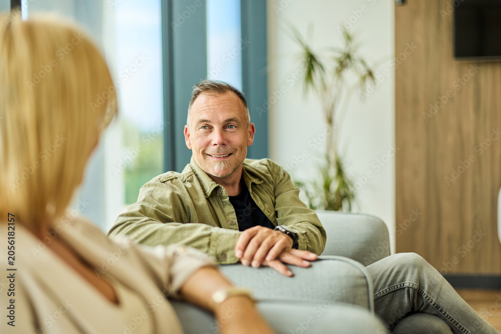 Fototapeta premium Relaxed Middle-Aged Man Having Friendly Conversation With Woman In Modern Office Lounge