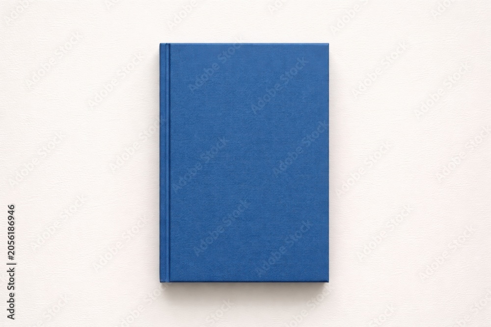 Fototapeta premium A simple closed blue hardcover book rests on a textured white background