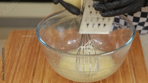 Chef is grating cheese in a glass bowl while cooking omelet