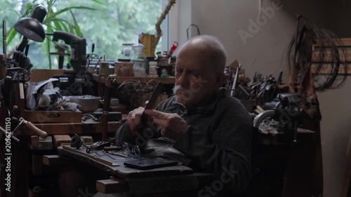 Elderly craftsman working in his old workshop, carefully restoring collectible Japanese bladed weapons