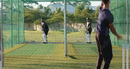 Diverse cricket teammates starting drill, pause, bowling, batting, retrieving balls in nets