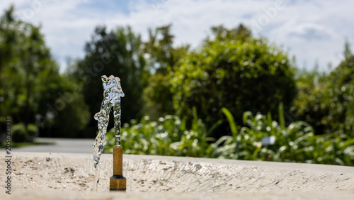 Public drinking fountain in urban green space providing access to potable water during hot weather, climate adaptation and sustainable city concept with ample copy space