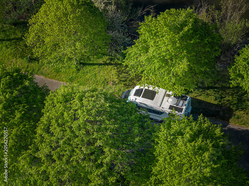 Camper van parked by canal surrounded by trees in Belgium