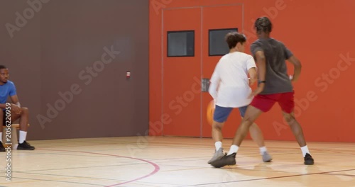 Faking crossover man dribbling basketball at gym for layup with male defender contesting