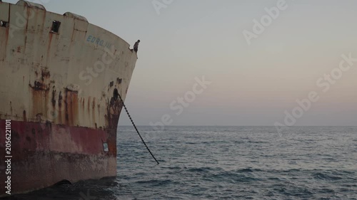 Tourist diving from rusty old shipwreck near the coastline on sunset