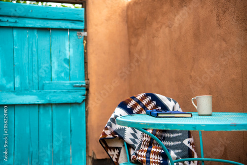 Canvastavla Cozy morning on a adobe patio in Santa Fe, New Mexico with a turquoise metal table with coffee, blanket and journal next to an adobe wall