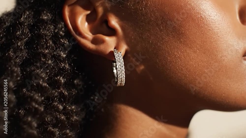 Close up of Black woman wearing diamond hoop earrings in golden sunlight