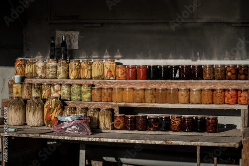 Foto Colorful homemade Armenian pickled vegetables and sweet fruit preserves in glass jars at a rustic roadside stall