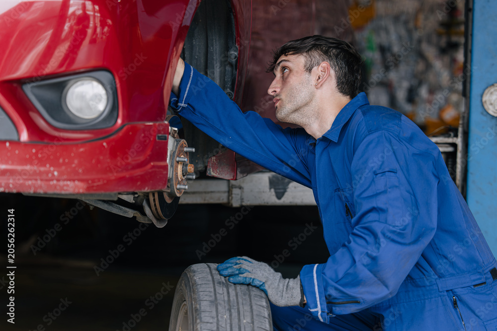Fototapeta premium Auto mechanic worker changing car tire in auto workshop garage, Vehicle tyre maintenance service