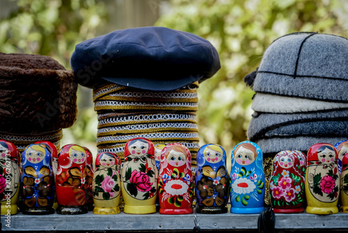 Schilderij op canvas Vibrant Matryoshka dolls displayed alongside various traditional Russian hats at an outdoor market stall
