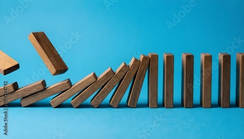 Wooden dominoes falling in a diagonal line against a bright blue background