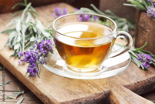 Quadro su tela Lavender herbal tea in a glass cup with flowers on wooden rustic background, clo