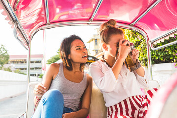 Thailand, Bangkok, two friends riding tuk tuk taking pictures with an old camera