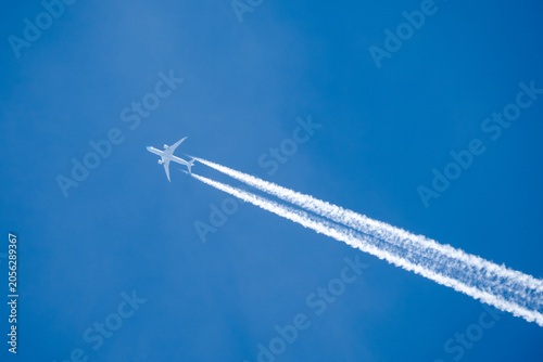 twin engined jet liner aircraft with contrails, in flight at high altitude, clear blue sky