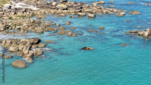 Spektakuläre Luftaufnahme vom Plage de Boutrouilles: Imposante, helle Granitfelsen liegen eingebettet im glasklaren, leuchtend türkisfarbenen Wasser des Atlantiks.