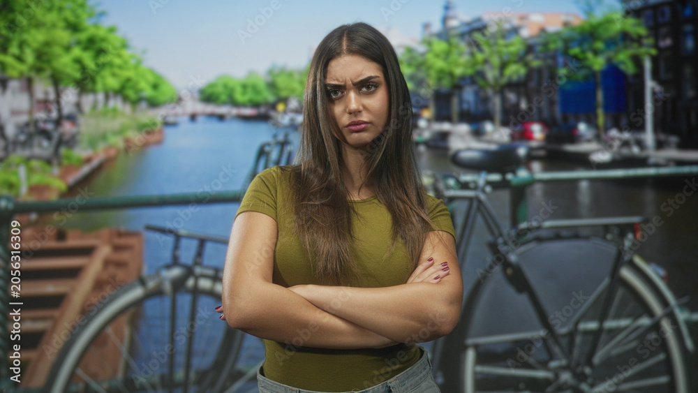 Fototapeta premium Woman claps hands on street canal bridge beside bicycle, then stands with arms crossed and frowning; frustration defiance.