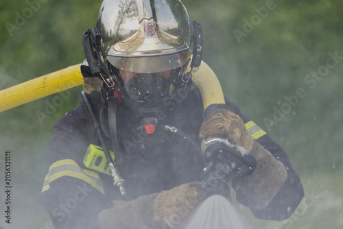 Fotografía Firefighter in full protective gear operating hose during training exercise
