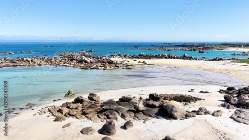 Eine beeindruckende Luftansicht vom Plage de Boutrouilles, bei der sanfte, weiße Wellenmuster auf den hellen Sandstrand und die charakteristischen, dunklen Felsformationen treffen.