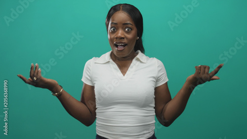 Valokuva Woman laughing with hands raised, mouth open and eyes closed, white polo shirt with bracelets in a studio teal backdrop; joy celebration