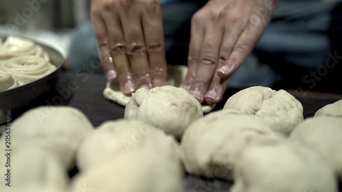 Hands kneading dough for making flaky laccha paratha during food preparation.