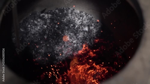 Cinematic shot of glowing coal fire burning inside traditional tandoor oven.