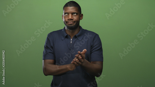 Konstfotografi Man clapping hands with an eye roll and sardonic expression, navy polo visible in green studio setting; dry sarcasm