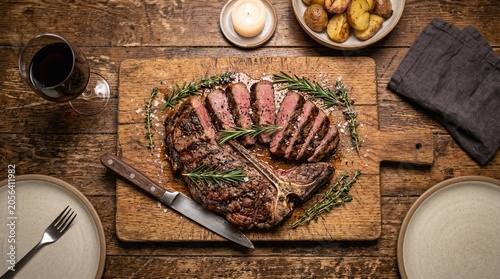 Schilderij op canvas Perfectly grilled porterhouse steak sliced on a rustic wooden cutting board serv
