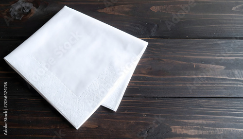 Folded white cotton handkerchief or napkin on dark wooden table background