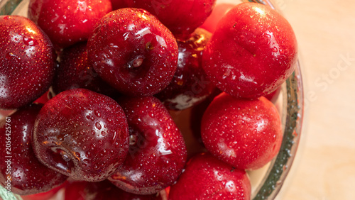 Close up of fresh ripe red cherries with water drops in a glass bowl on wooden background