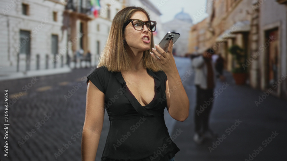 Obraz premium Woman holding smartphone to mouth, speaking into phone with visible cleavage on a street; concentration independence.