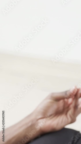 Vertical video: Moving right hand pinching, twisting on bent knee in dark pants at home with phone
