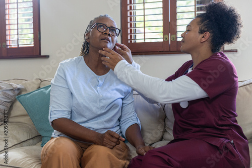 Foto African American caregiver in maroon scrubs adjusting senior woman's lower jaw a