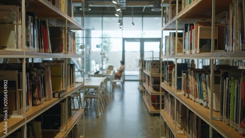 Fotografie Library shelves and aisle in soft bokeh, books and study tables receding into a blurred interior; background backdrop copyspace calm