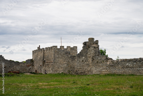 Obraz na plátně the stone fortification walls and ramparts of an ancient castle, set against a backdrop of an overcast sky and an expansive green field