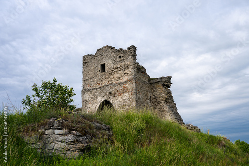 Obraz na płótnie the solitary, weathered stone ruins of an ancient tower standing atop a lush, gr