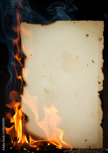 Burning blank paper with flames, smoke and charred edges on dark background
