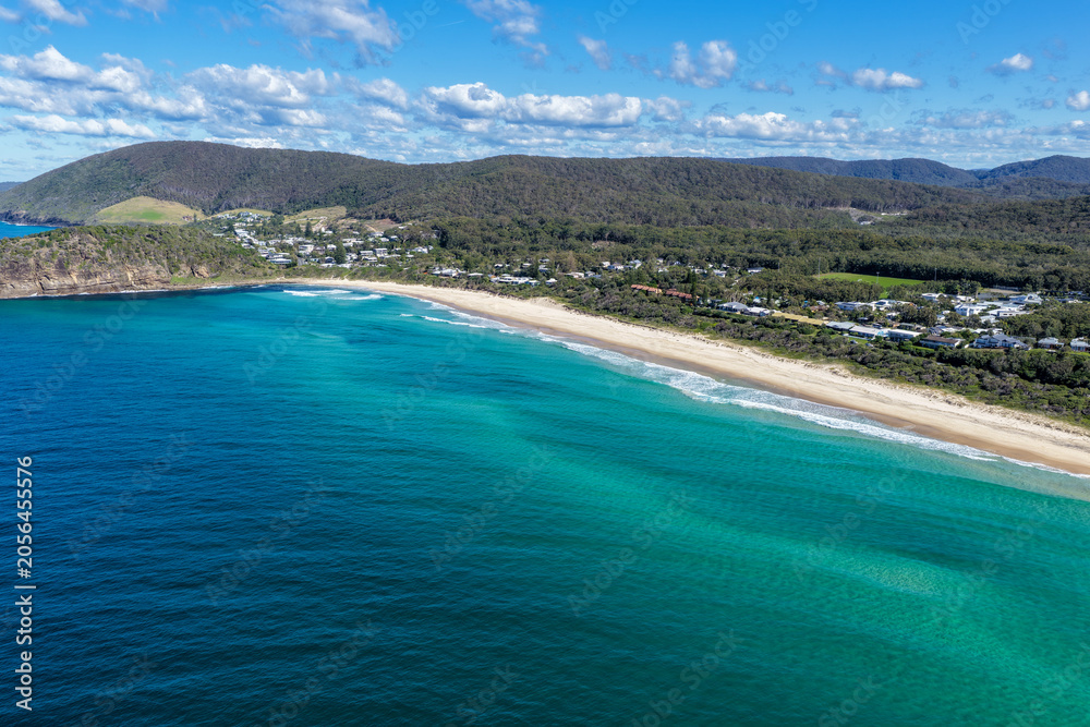Fototapeta premium Aerial scene capturing Boomerang Beach near Pacific Palms, NSW, Australia, with residential homes and native bushland visible in the background. The sandy shoreline, clear ocean waters and landscape.