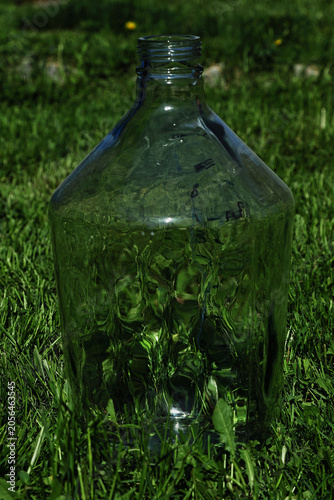 Vászonkép A close-up shot of a large green glass carboy or demijohn bottle standing outdoors on fresh green grass
