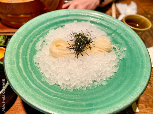 japanese cold noodles on ice with nori garnish in teal ceramic plate