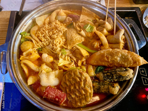 spicy korean tteokbokki pot with ramen and fish cakes on induction cooktop top down view