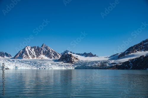 Bild auf Leinwand Glacier meeting the Arctic Ocean at the base of the mountains in Bjornfjorden, S