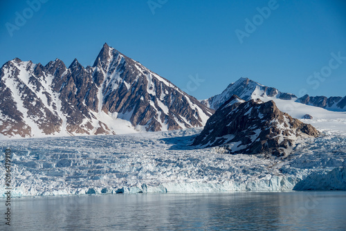 Bild auf Leinwand Glacier meeting the Arctic Ocean at the base of the mountains in Bjornfjorden, S
