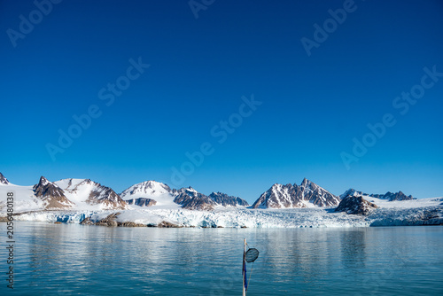 Bild auf Leinwand Glacier meeting the Arctic Ocean at the base of the mountains in Bjornfjorden, S
