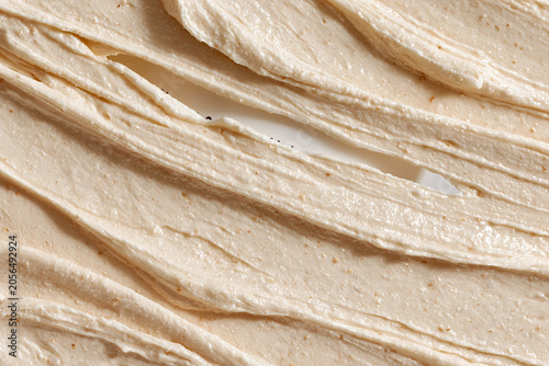 Macro Close-up Texture of a Creamy Beige Exfoliating Face Scrub or Body Mask with Natural Grains, Showing Thick Swatches and Ridges for Skincare Product Background and Beauty Industry Marketing.