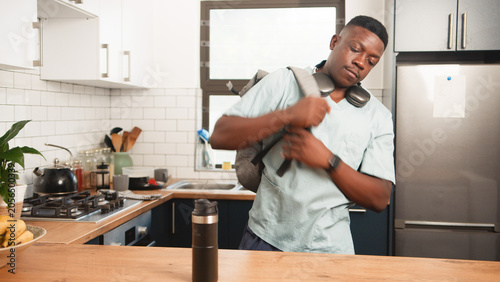 Young Healthcare Worker Leaving Kitchen With Backpack And Travel Mug Before Morning Shift